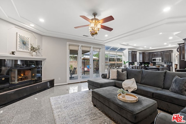 living room featuring ceiling fan, a premium fireplace, a raised ceiling, and french doors