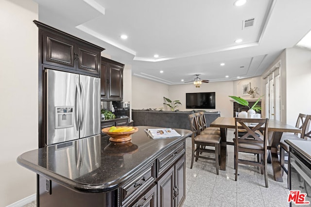 kitchen featuring ceiling fan, dark brown cabinets, a center island, stainless steel fridge with ice dispenser, and a raised ceiling