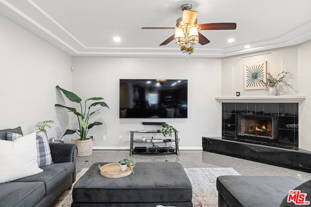 living room featuring a fireplace, a raised ceiling, and ceiling fan