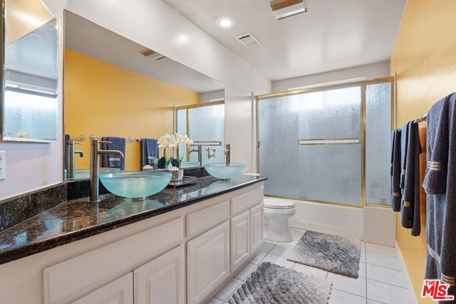 full bathroom featuring vanity, tile patterned floors, shower / bath combination with glass door, and toilet