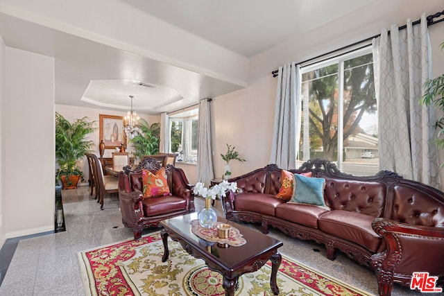 living room featuring a notable chandelier and a tray ceiling