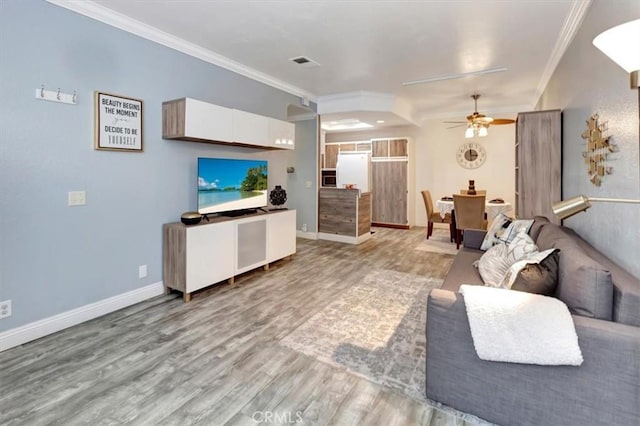 living room featuring crown molding, ceiling fan, and light hardwood / wood-style flooring