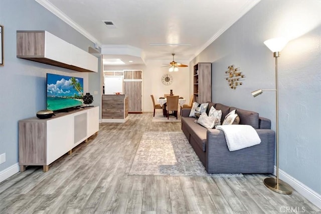 living room with light hardwood / wood-style flooring, ornamental molding, and ceiling fan