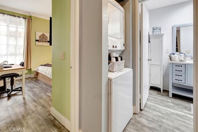 laundry room featuring stacked washer / dryer and light hardwood / wood-style flooring