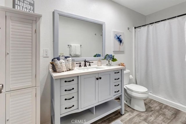 bathroom featuring vanity, wood-type flooring, toilet, and walk in shower