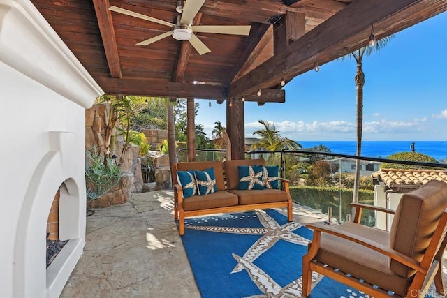 view of patio / terrace featuring a water view, ceiling fan, and an outdoor living space with a fireplace