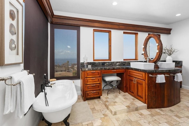 bathroom featuring recessed lighting, a freestanding tub, vanity, and stone tile floors
