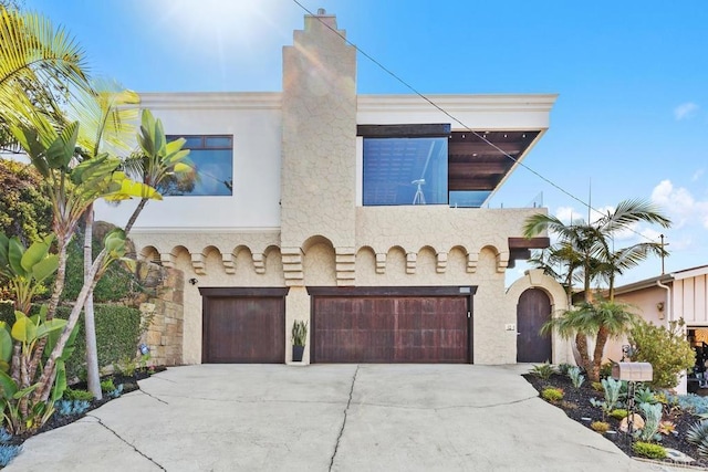 mediterranean / spanish home with concrete driveway, stucco siding, a chimney, and an attached garage