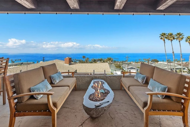 view of patio with a water view and an outdoor living space with a fire pit