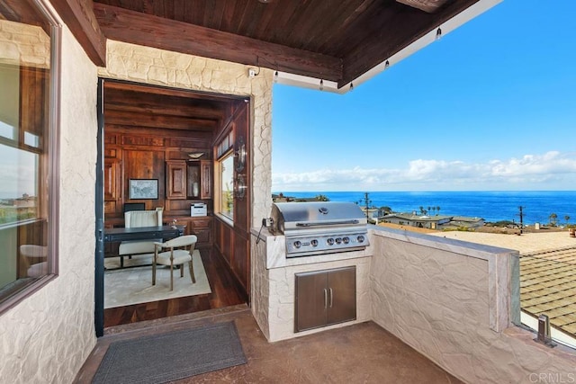 view of patio featuring a grill, an outdoor kitchen, and a water view