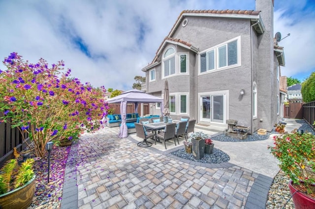 back of property with a gazebo, an outdoor hangout area, and a patio area