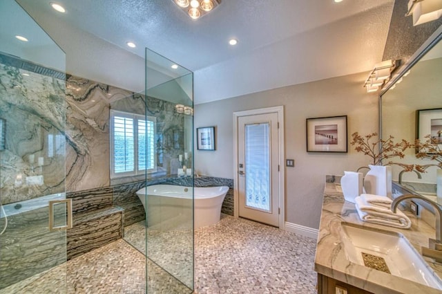 bathroom featuring plus walk in shower, vaulted ceiling, and vanity