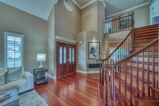 foyer with a towering ceiling, wood-type flooring, and ornamental molding