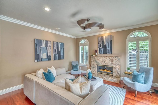 living room featuring hardwood / wood-style flooring, ornamental molding, a premium fireplace, and a healthy amount of sunlight