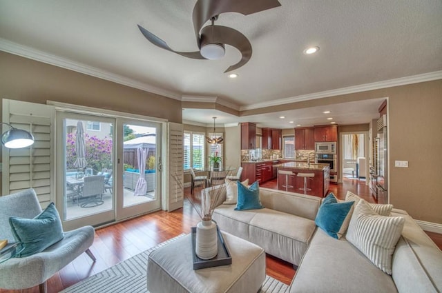 living room featuring ornamental molding, sink, ceiling fan, and light hardwood / wood-style flooring