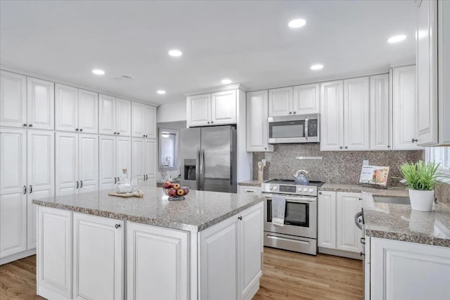 kitchen featuring stainless steel appliances, a kitchen island, and white cabinets