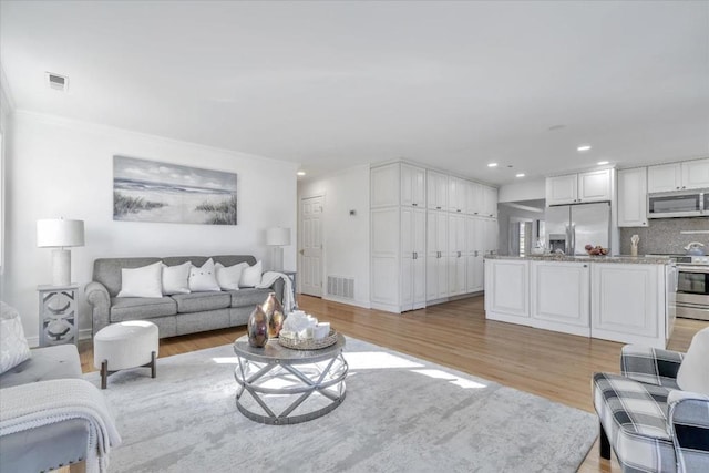 living room with crown molding and light hardwood / wood-style flooring