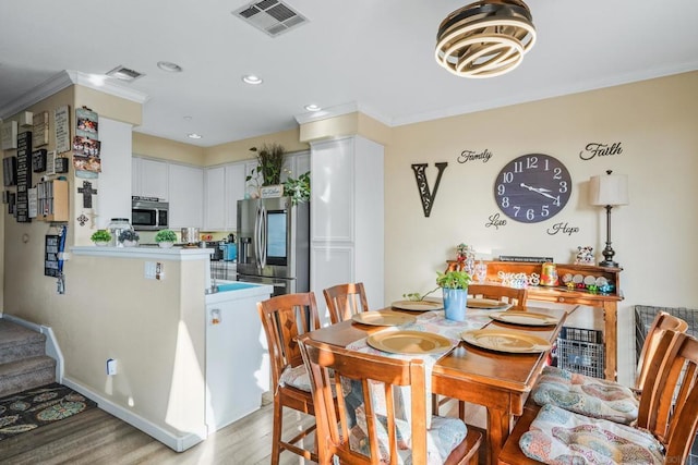 dining space with crown molding and light wood-type flooring