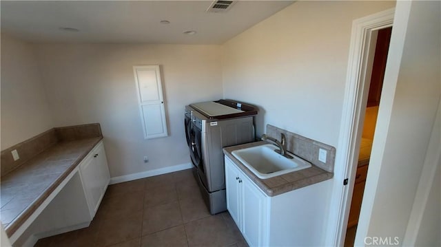 washroom with cabinet space, visible vents, tile patterned floors, washing machine and dryer, and a sink