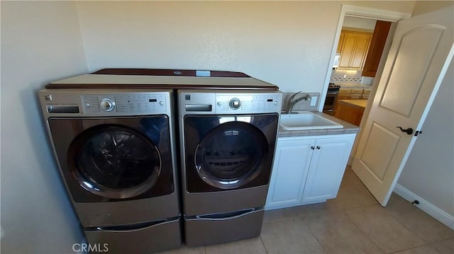 washroom with a sink, light tile patterned flooring, washing machine and clothes dryer, and cabinet space