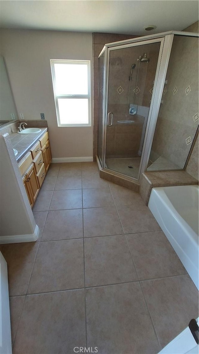 bathroom featuring a garden tub, a sink, a shower stall, tile patterned floors, and double vanity