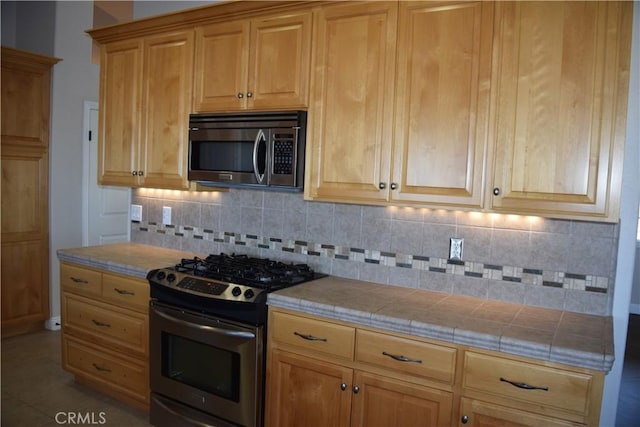 kitchen with stainless steel appliances, tile countertops, and tasteful backsplash