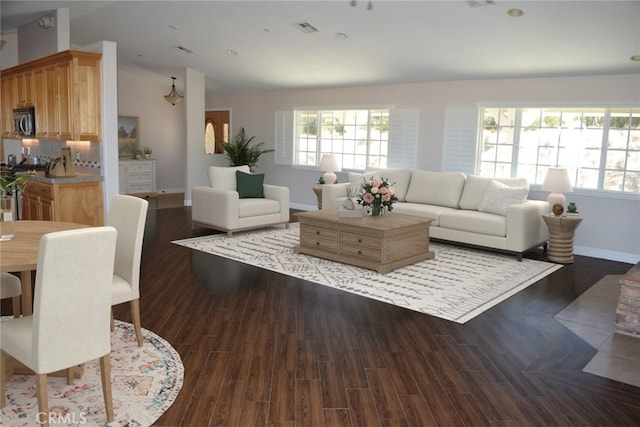 living room featuring a wealth of natural light, lofted ceiling, and dark wood-style flooring