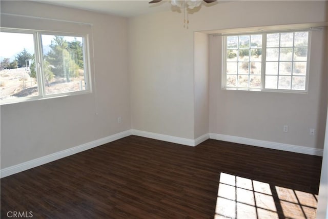 empty room with dark wood-style floors, baseboards, and a ceiling fan