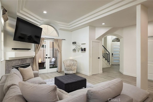 living room with french doors, a premium fireplace, and light hardwood / wood-style floors