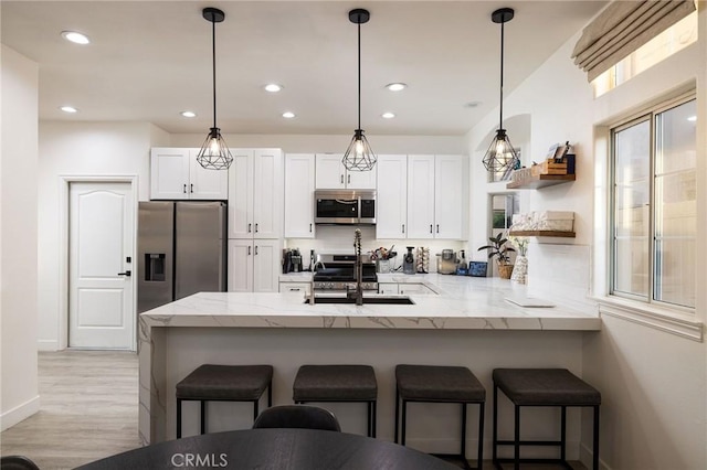 kitchen featuring appliances with stainless steel finishes, kitchen peninsula, sink, and white cabinets