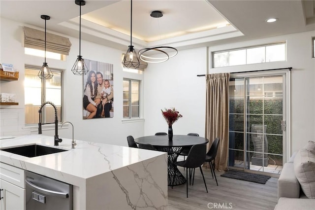 kitchen with white cabinetry, sink, light stone countertops, and a raised ceiling