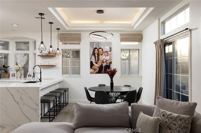 dining space featuring dark hardwood / wood-style flooring, a raised ceiling, and sink