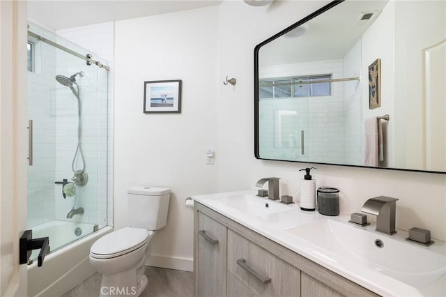 full bathroom featuring bath / shower combo with glass door, hardwood / wood-style floors, vanity, and toilet