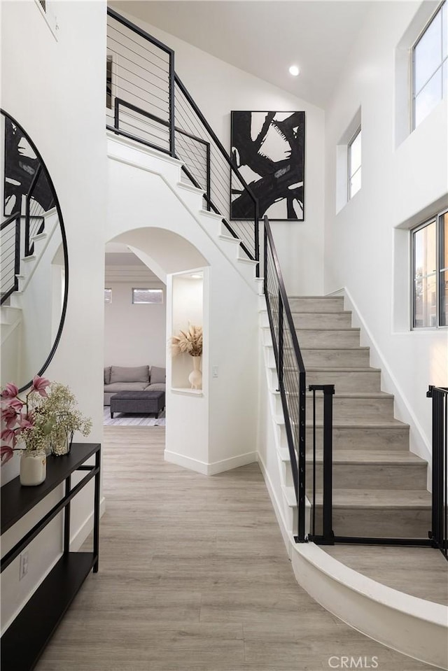 staircase featuring hardwood / wood-style flooring and a towering ceiling