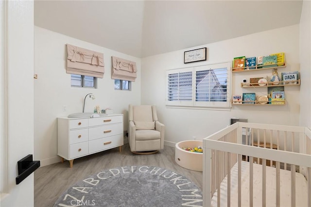 bedroom featuring light wood-type flooring and a crib