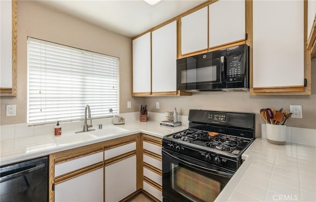 kitchen featuring sink, black appliances, and white cabinets