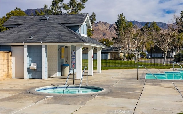 view of swimming pool with a mountain view, a patio area, and a hot tub