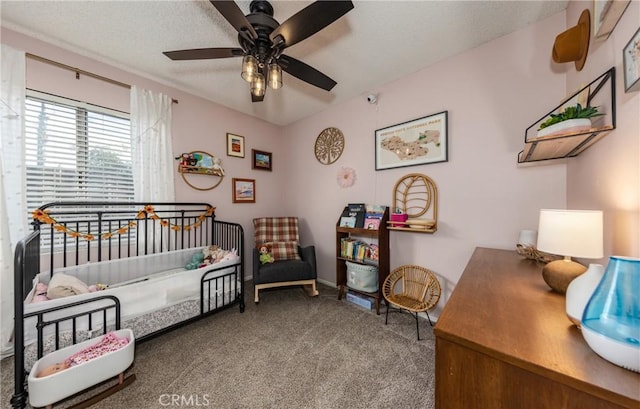 carpeted bedroom featuring a crib and ceiling fan