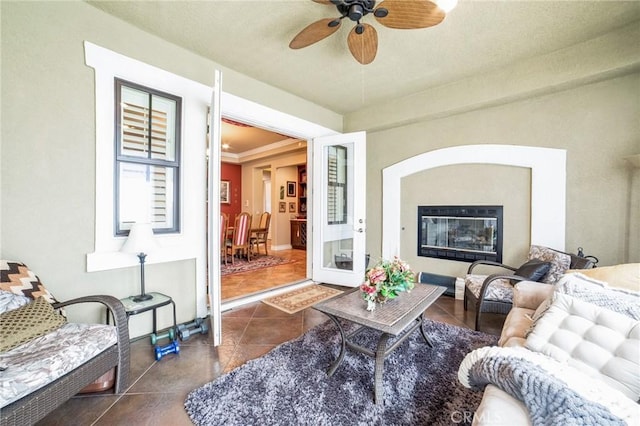 living room featuring crown molding, dark tile patterned flooring, and ceiling fan