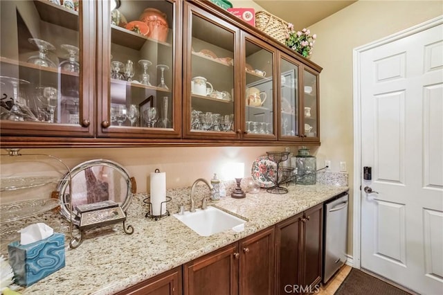 bar featuring light stone counters, sink, and stainless steel dishwasher