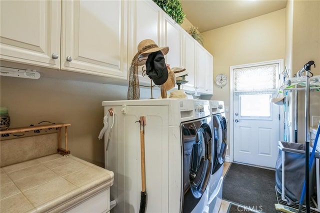 laundry room featuring separate washer and dryer and cabinets