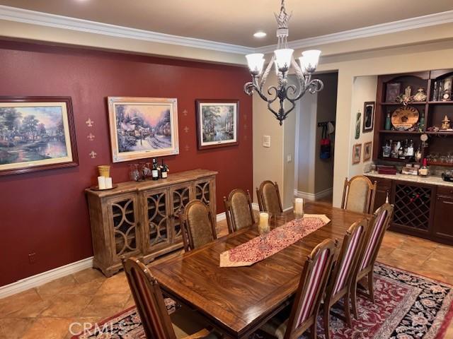 tiled dining area with crown molding and a chandelier