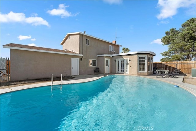 view of swimming pool featuring a patio, french doors, fence, and a fenced in pool