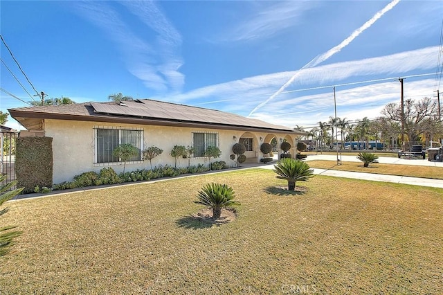 view of front of property featuring a front lawn and solar panels