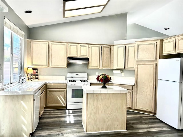 kitchen featuring white appliances, vaulted ceiling, a kitchen island, and light brown cabinets