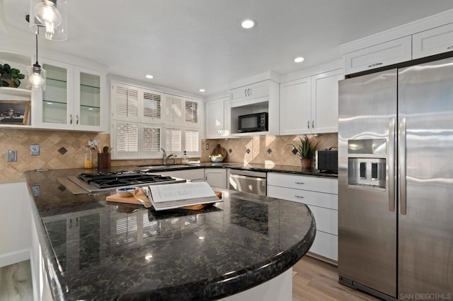 kitchen featuring white cabinetry, hanging light fixtures, decorative backsplash, and appliances with stainless steel finishes