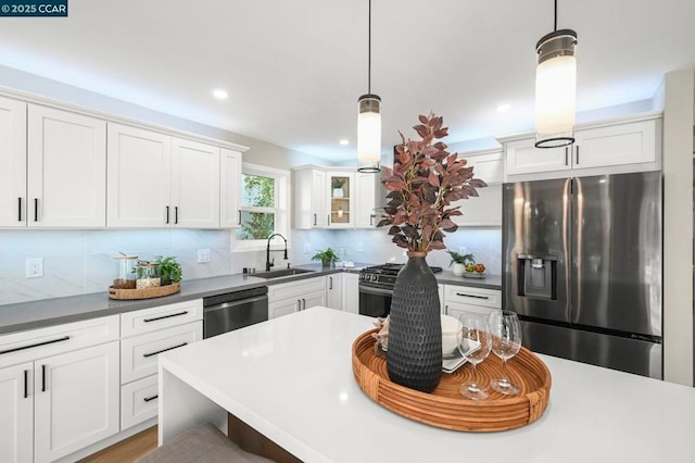 kitchen with sink, white cabinetry, decorative light fixtures, appliances with stainless steel finishes, and backsplash