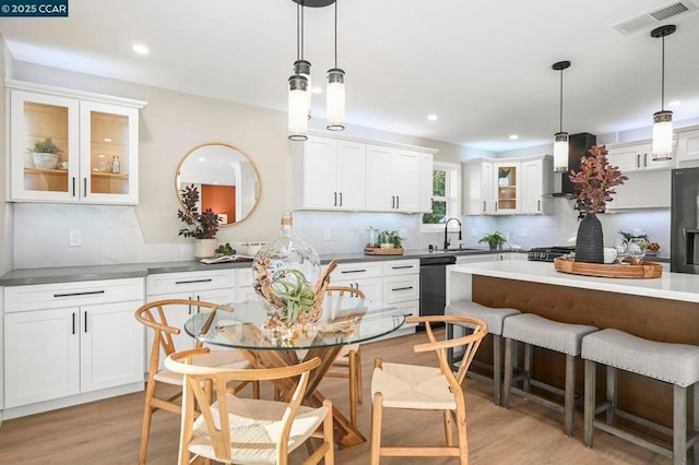 kitchen featuring hanging light fixtures, wall chimney exhaust hood, and white cabinets