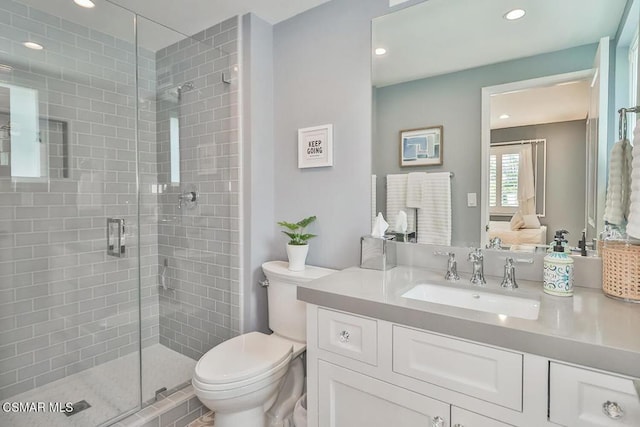 bathroom featuring vanity, a shower with door, and toilet