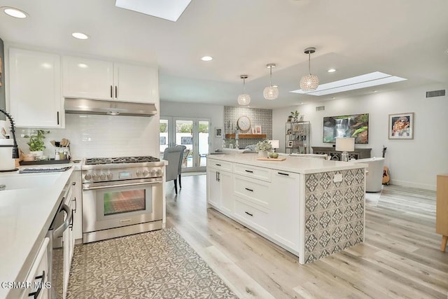 kitchen featuring white cabinetry, decorative light fixtures, a skylight, and stainless steel appliances